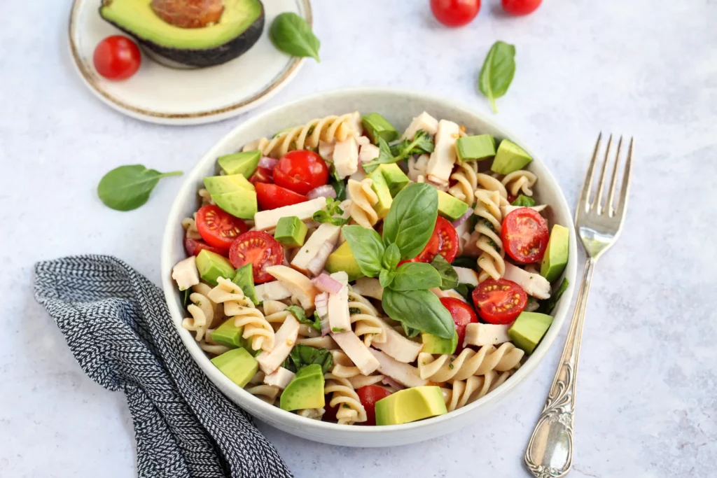 Chicken avocado pasta salad with cherry tomatoes and fresh basil